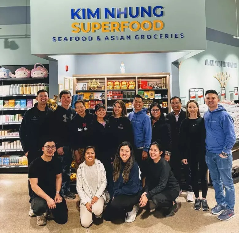 The Kim Nhung Superfood family and staff gathered together in the store, beneath the Kim Nhung Superfood sign.